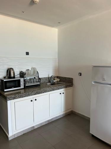 萨伊迪耶ALYA SAPHIR的厨房配有白色橱柜、水槽和冰箱。