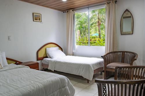 奎波斯城Tropical Bliss Pool Wi-Fi BBQ Near Quepos Manuel Antonio的一间卧室设有两张床、一个窗口和椅子