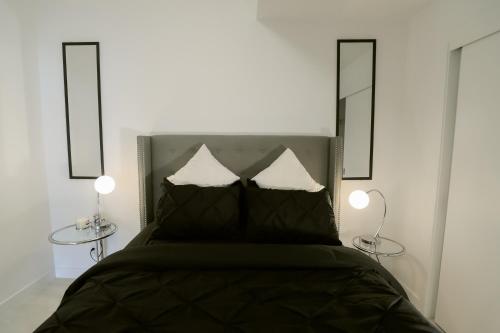 卡尔加里Vibrant & Modern Loft-style Walkout Near LRT的一间卧室配有一张带两张桌子和两盏灯的床。