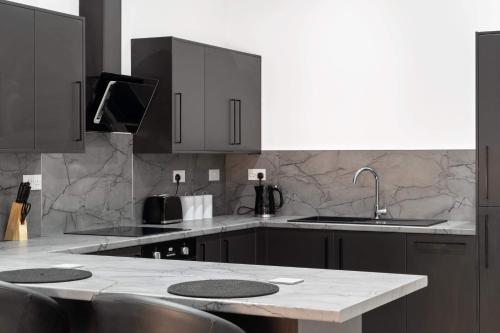 彼得伯勒Cowgate Luxury Apartments的厨房配有黑色橱柜和大理石台面