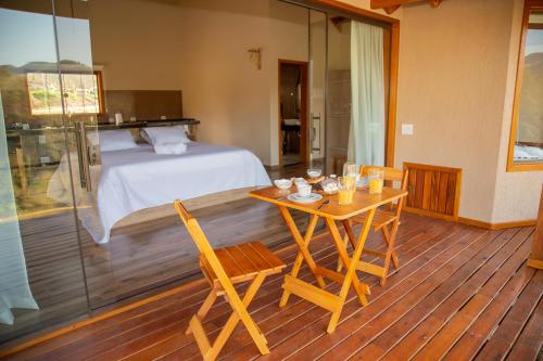 圣本图-杜萨普卡伊Chalé Pedra Madeira的卧室配有一张床和一张桌子及椅子