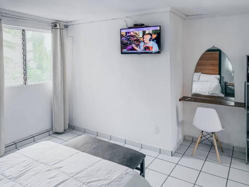 瓜达拉哈拉La Casa del Expositor的卧室配有一张床,墙上配有电视。