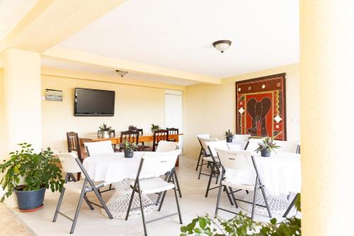 罗索La Maison 29的餐厅设有白色的桌椅和平面电视。