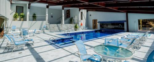 格拉玛多Hotel Serrano Gramado - Apto Particular 452的一个带桌椅的游泳池和一个游泳池