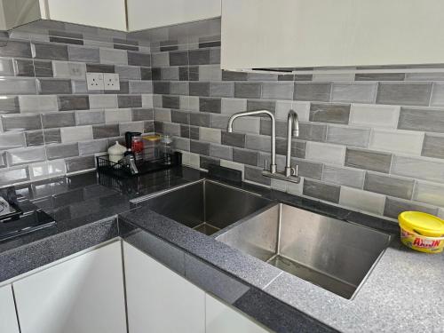 居銮TSK Homestay Taman Sri Kluang的厨房配有不锈钢水槽和灰色瓷砖