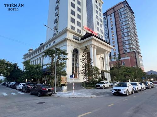 Thôn Dương PhẩmThiên Ân Hotel的白色的建筑,有汽车停在停车场