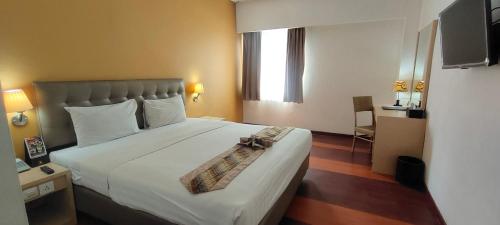 日惹阿朱酒店的酒店客房设有一张大床,上面有弓