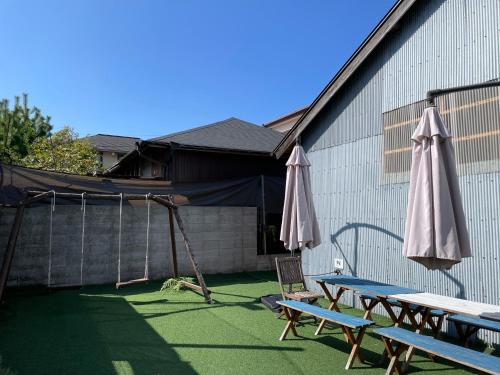 洲本市the terrace sumoto - Vacation STAY 24588v的庭院设有两张野餐桌和一把雨伞。