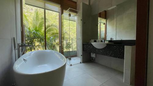三百岭La Isla Pranburi Beach Resort的带浴缸、水槽和窗户的浴室