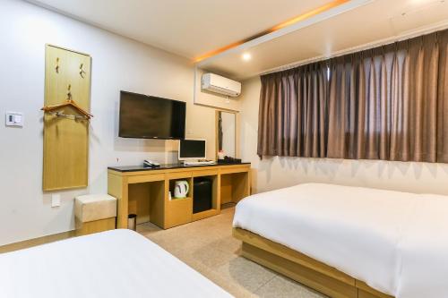 济州市Aliba Hotel的酒店客房设有两张床和电视。