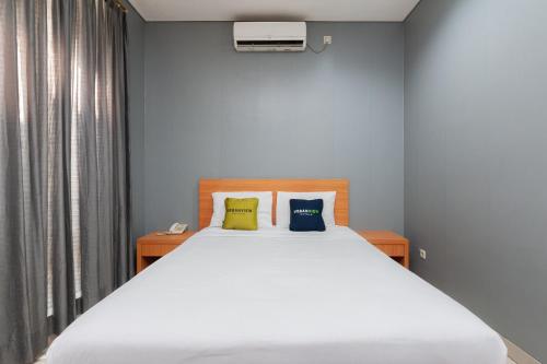雅加达RedDoorz Plus near Kelapa Dua Kebon Jeruk的卧室配有一张带两个枕头的大白色床