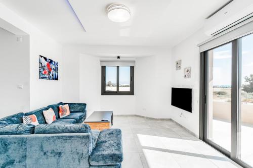 帕福斯Villa Elpida THREE by Ezoria Villas in Timi, Paphos的客厅配有蓝色的沙发和电视