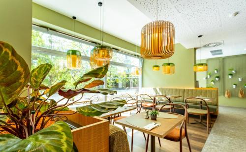 维也纳The Weekend Hotel的一间设有桌椅的餐厅,种植了植物