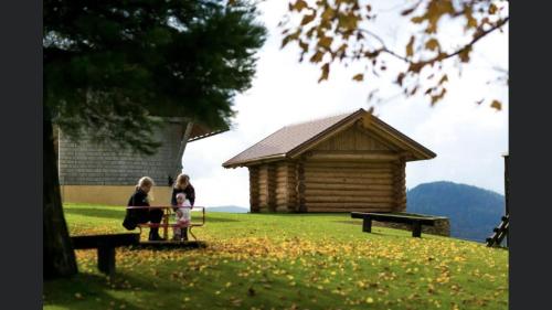 兹雷切Brunarica Macesen Smogavc的两个女人和一个孩子坐在小屋前面的长凳上