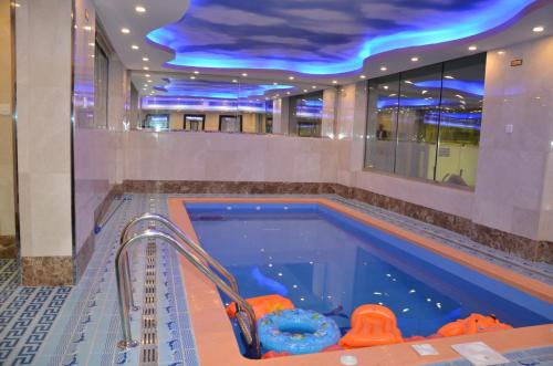 吉赞جولدن أرمادا جيزان Golden Armada Hotel的蓝色天花板建筑中的游泳池