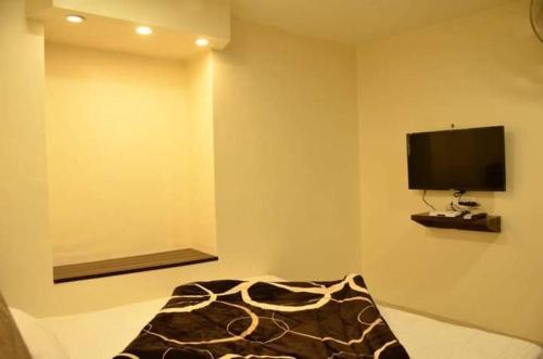 阿姆利则Hotel Bindra Paradise 800 Meter From Golden Temple的一间配有电视的房间和一张带毯子的床