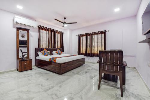 艾哈迈达巴德FabHotel Vishwa Palace的一间卧室配有一张床和一把椅子