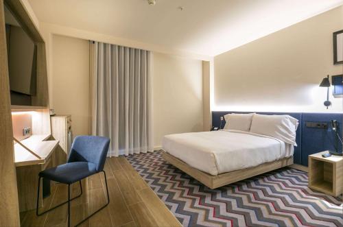 阿尔考本达斯Hampton By Hilton Alcobendas Madrid的配有一张床和一把椅子的酒店客房