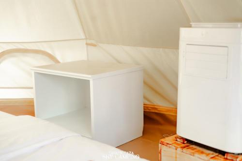 格兰岛Tawaen Caza Sky Camping的一间设有两张白色桌子的房间,位于床边