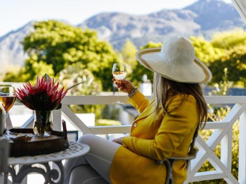 弗朗斯胡克Fleur du Soleil Luxury Guesthouse的坐在桌子旁的女人,喝一杯酒