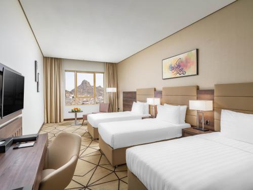 麦加Wirgan Hotel Al Nour的酒店客房设有两张床和一台平面电视。
