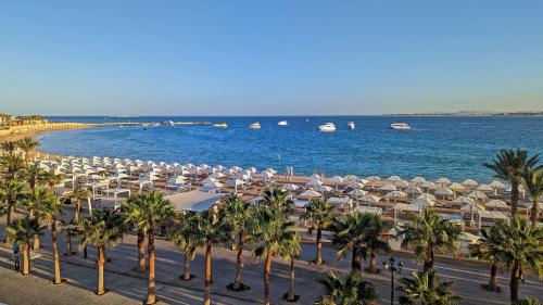 赫尔格达KaiSol Romance Resort Sahl Hasheesh - Adults Only的海滩上拥有遮阳伞和棕榈树,还有大海