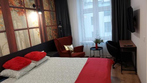 罗兹theApartments Gdańska的一间卧室配有一张带红色枕头的床和一张书桌