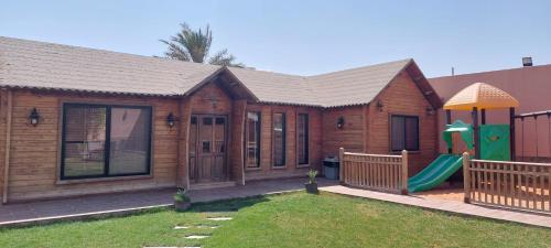 利雅德Antola Resort Al Rimal的庭院内带游乐场的木屋