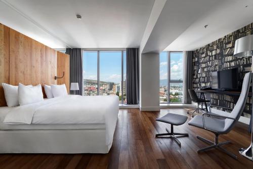 第比利斯第比利斯假日酒店 的卧室配有白色的床、书桌和椅子
