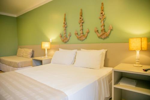 乌巴图巴Pousada Villa Di Enzo的一间卧室配有一张带两盏灯的大型白色床。