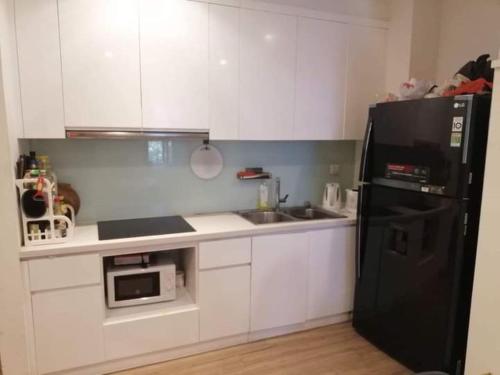 河内Park 12 Homestay的厨房配有白色橱柜和黑色冰箱。