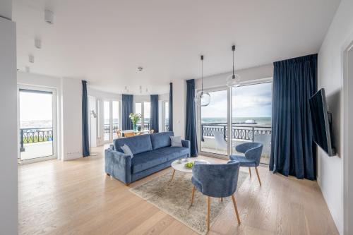 达尔沃沃Marina Royale Darłowo - Apartamenty Vista Mar nad morzem的客厅配有蓝色的沙发、桌子和椅子