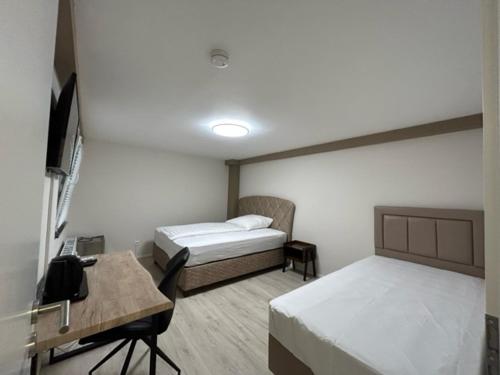 勒沃库森Rheinischer Hof Appartements的客房设有两张床、一张桌子和一台电视机。