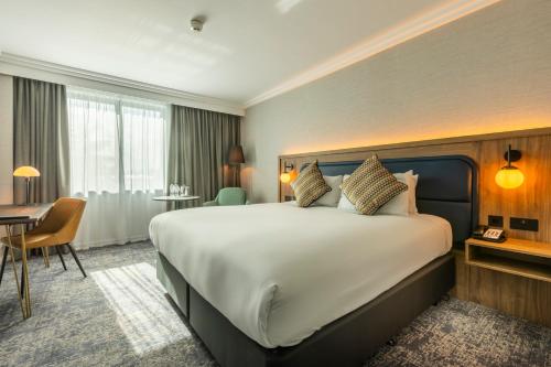 霍尔假日皇冠曼切斯特机场酒店的酒店客房设有一张大床和一张书桌。