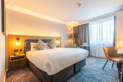 霍尔假日皇冠曼切斯特机场酒店的酒店客房设有一张大床和一张书桌。