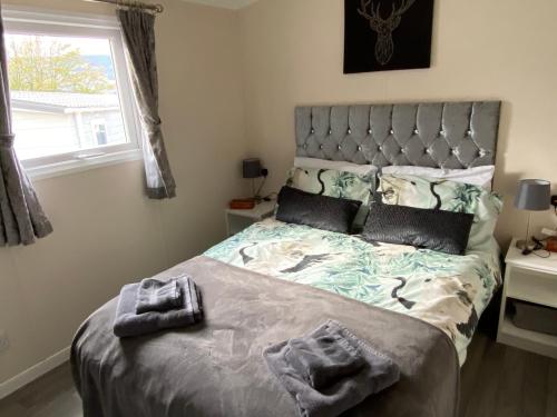 科弗Lovely new caravan by Loch Long的一间卧室设有一张大床和大窗户