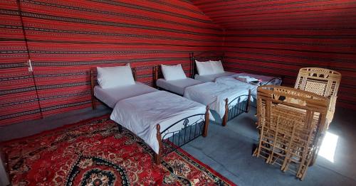 Al WāşilSand Delight Camp的红色墙壁的客房内的两张床