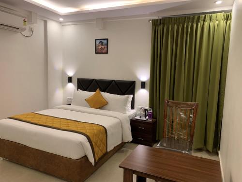 班加罗尔Hotel Le Grandeur的一间卧室配有一张床、一张桌子和绿色窗帘