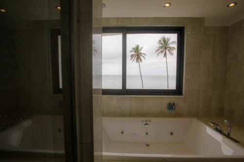 马普托Cowork Lab Suites的带浴缸的浴室和棕榈树窗户。
