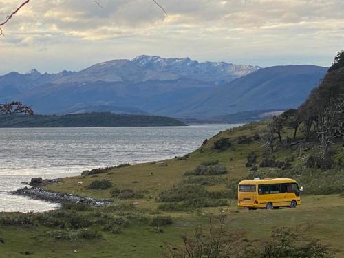 纳塔列斯港Camperbus Apawata的停在水体旁边的山坡上的黄色货车