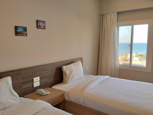 赫尔格达Al Dora Residence Suites Hurghada的酒店客房设有两张床和窗户。