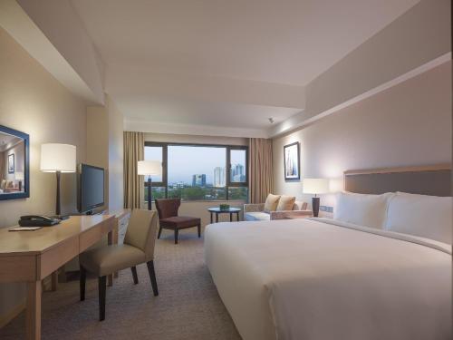 马尼拉马尼拉新世界酒店的酒店客房设有一张大床和一张书桌。