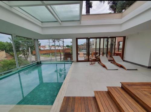 卡内拉Canela Cantinho dos Sonhos的玻璃墙房子内的游泳池