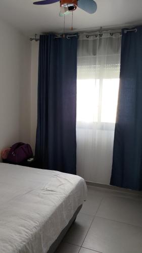 哈德拉Green Park的一间卧室配有一张带蓝色窗帘的床和一扇窗户