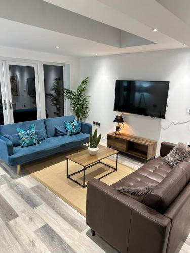 弗姆比Dora Cottage的客厅配有蓝色的沙发和平面电视。