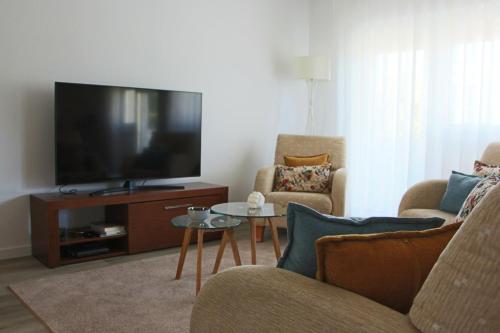 卡斯卡伊斯ARRUDA LUXURY APARTMENT with AC的客厅配有电视、2把椅子和1张桌子