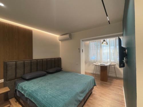 地拉那Downtown Studio Apartments的一间卧室配有一张床、一张桌子和一个窗户。