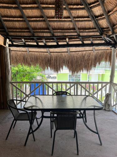 Playa Punta ArenaEco-Conscious Oasis Punta Arena 01的茅草屋顶下的一张桌子和两把椅子