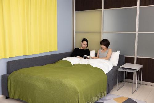 端岛Guest House Gifuhashima COCONE / Vacation STAY 30285的两个女人坐在卧室的床上