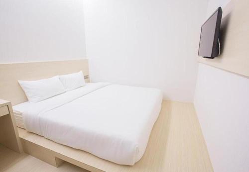 新山Minimalist Hotel的卧室配有白色的床和墙上的电视